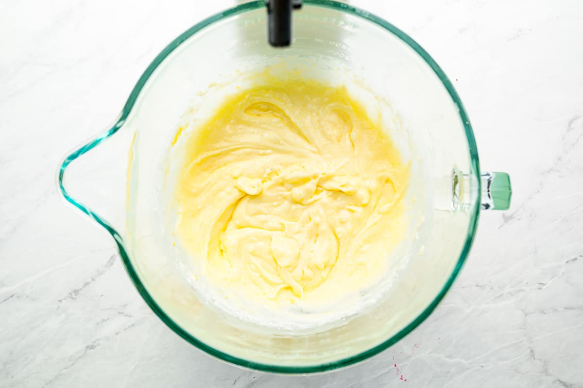 A bowl of yellow batter in a mixer.