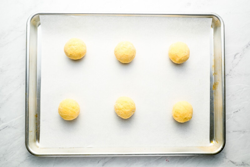 A baking sheet with six yellow eggs on it.