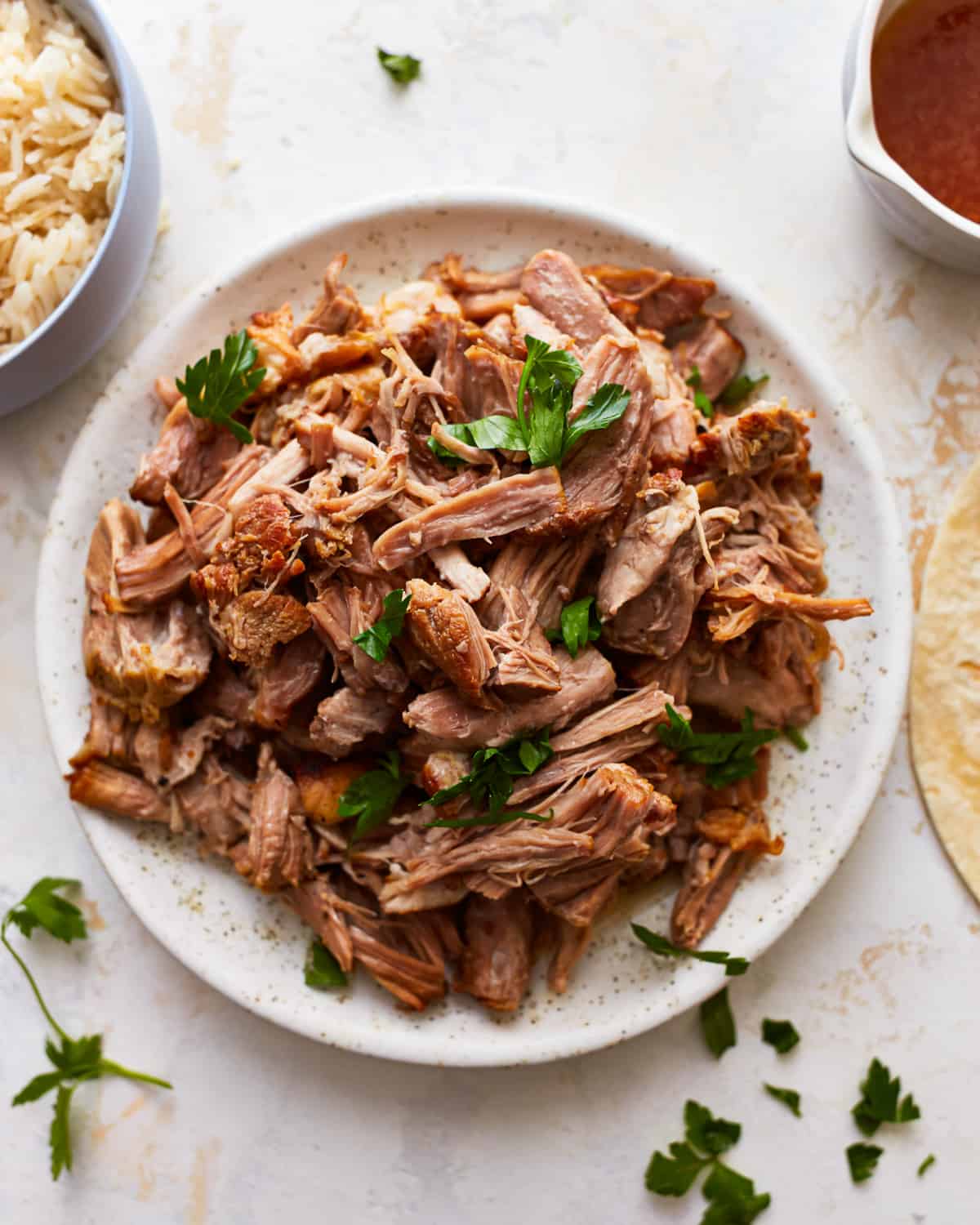 shredded instant pot pork shoulder on a white plate with cilantro.