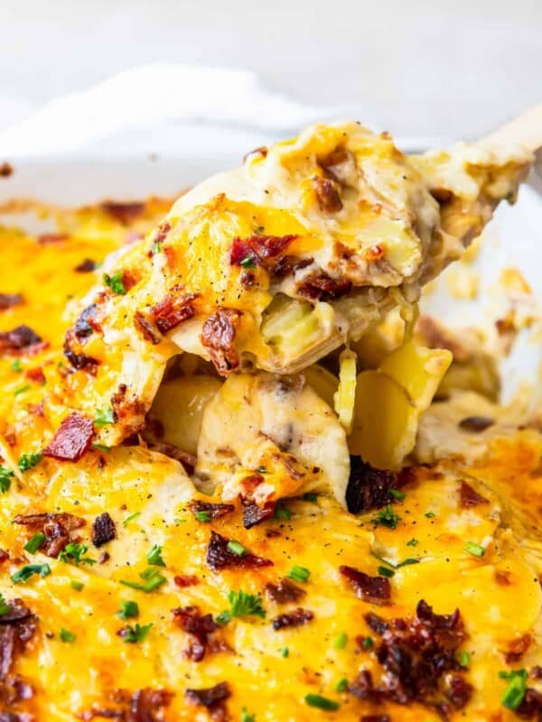 spoon lifting up loaded scalloped potatoes