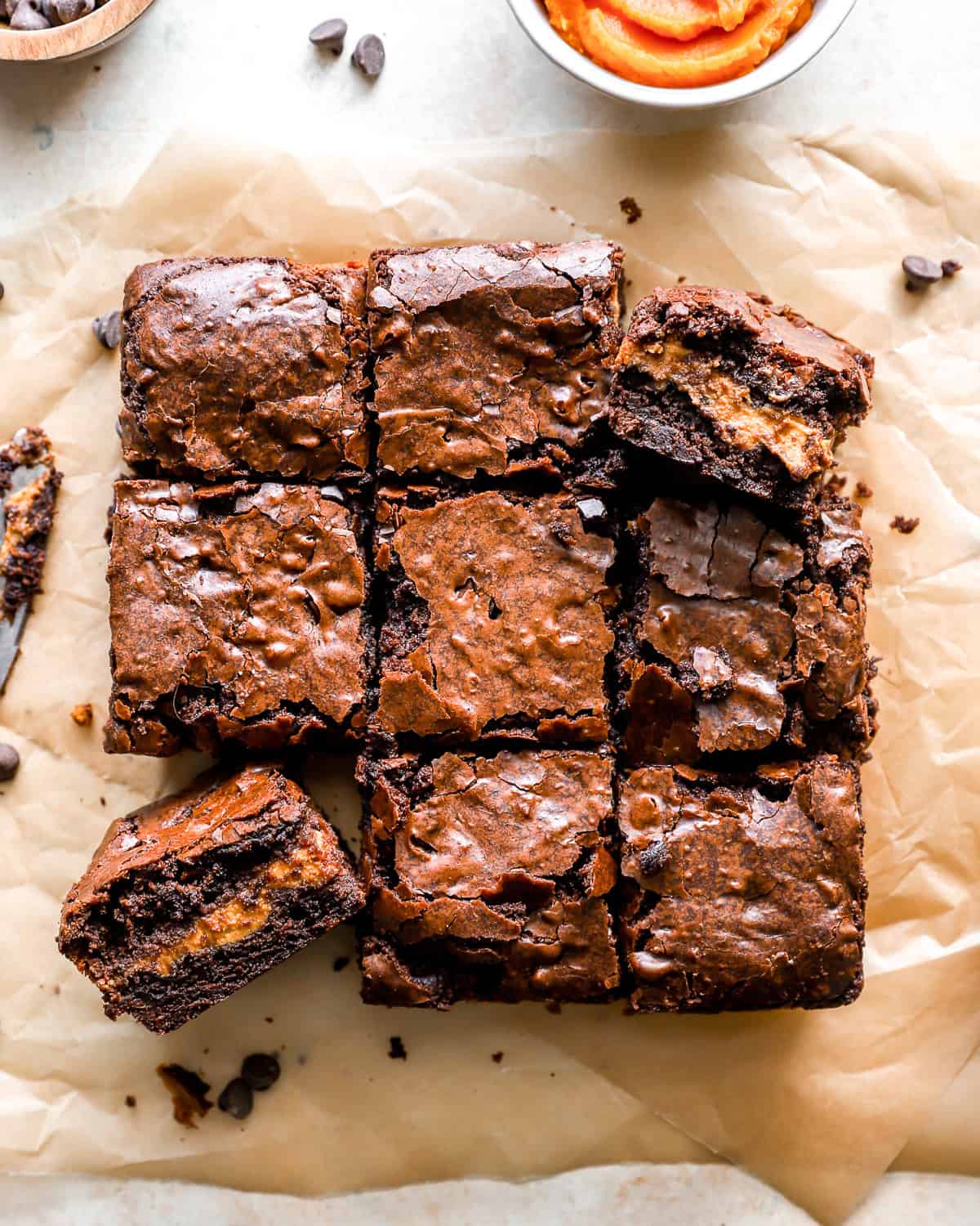 overhead view of cut pumpkin brownies on parchment paper.