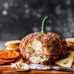 Pumpkin cheese ball on a cutting board with crackers.