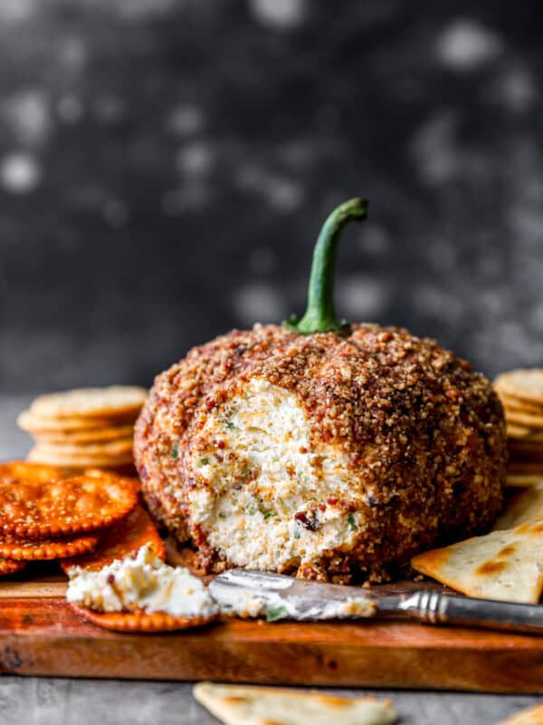 Pumpkin cheese ball on a cutting board with crackers.