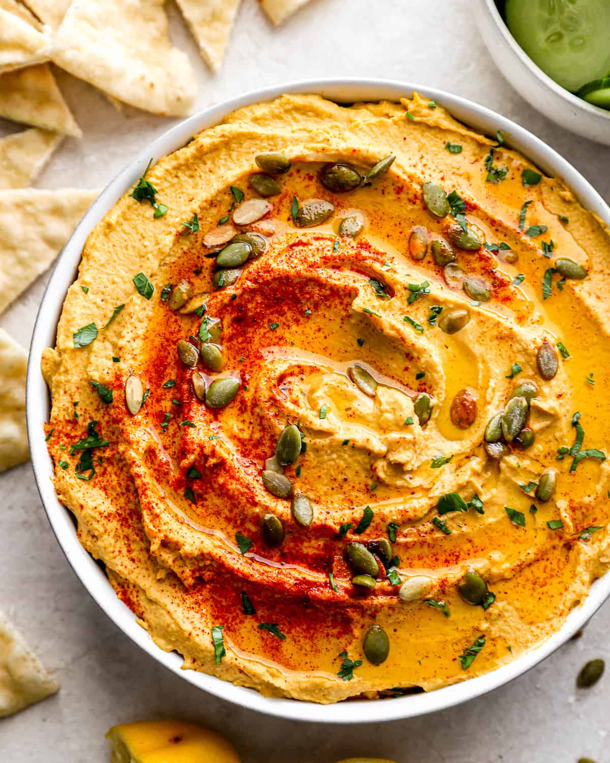 A bowl of pumpkin hummus with pita chips.