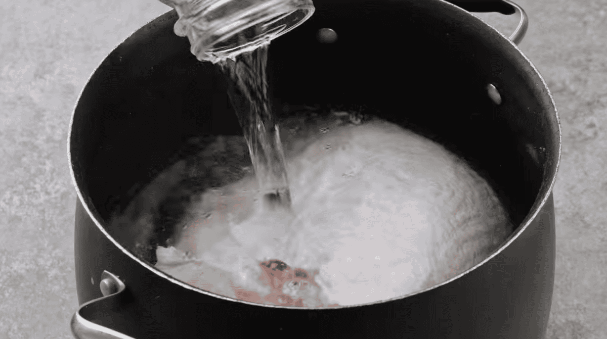 pouring water over a raw turkey breast in a bath of brine.