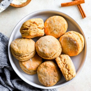 Pumpkin biscuits on a plate with cinnamon sticks.