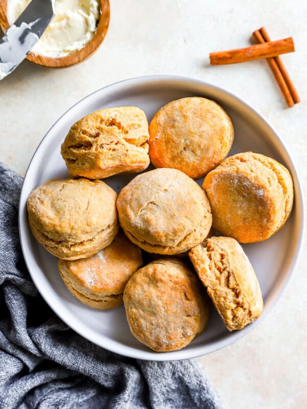 Pumpkin biscuits on a plate with cinnamon sticks.