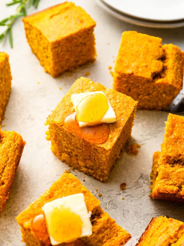 Cornbread squares with butter and honey on a plate.