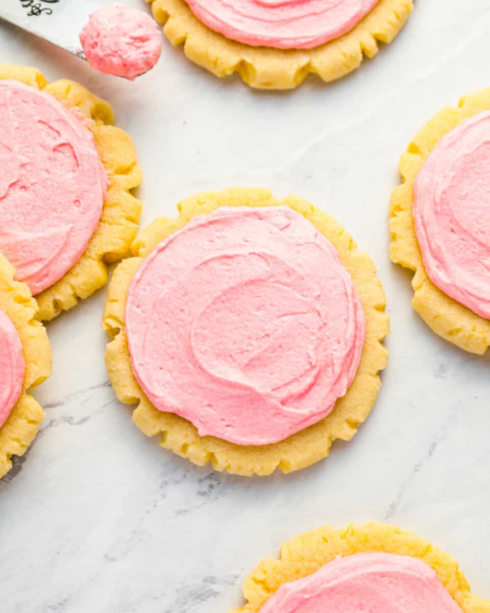 Pink frosted sugar cookies on a marble countertop.