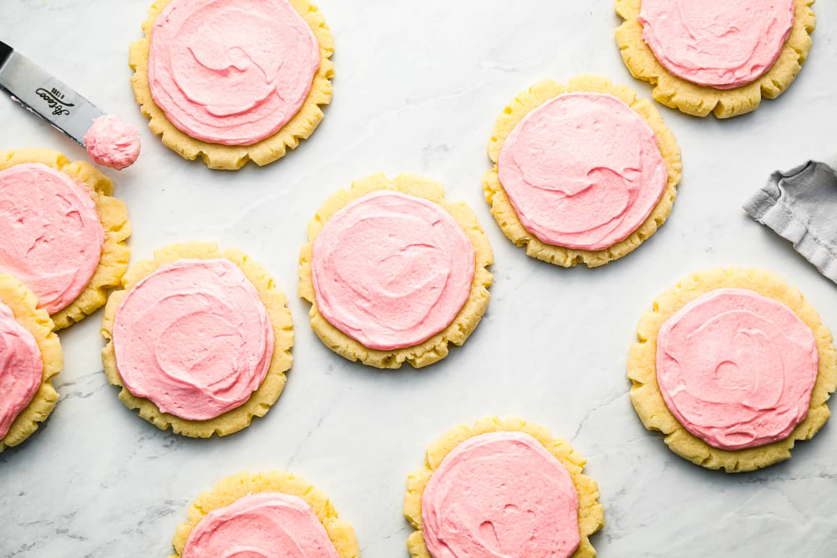 Pink swig sugar cookies on a marble countertop.