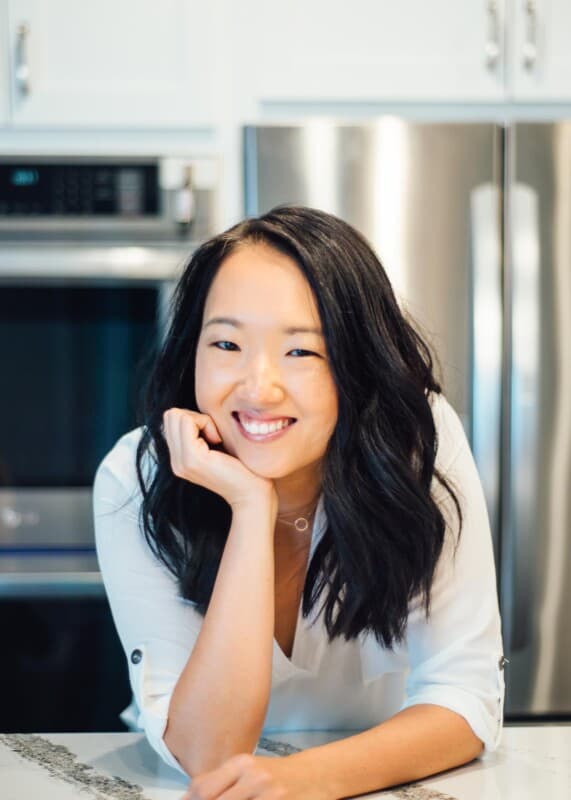 An Asian food blogger smiling in a kitchen.