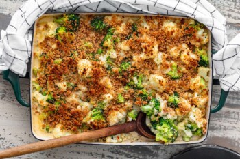 A cauliflower gratin dish served with a wooden spoon.
