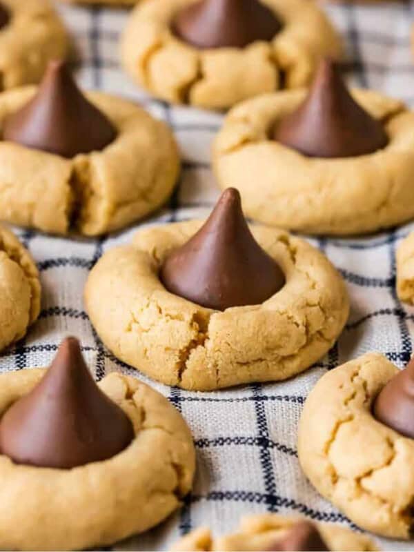 Peanut butter cookies with chocolate kisses, known as hershey kiss cookies or peanut butter kiss cookies, arranged on a baking sheet.