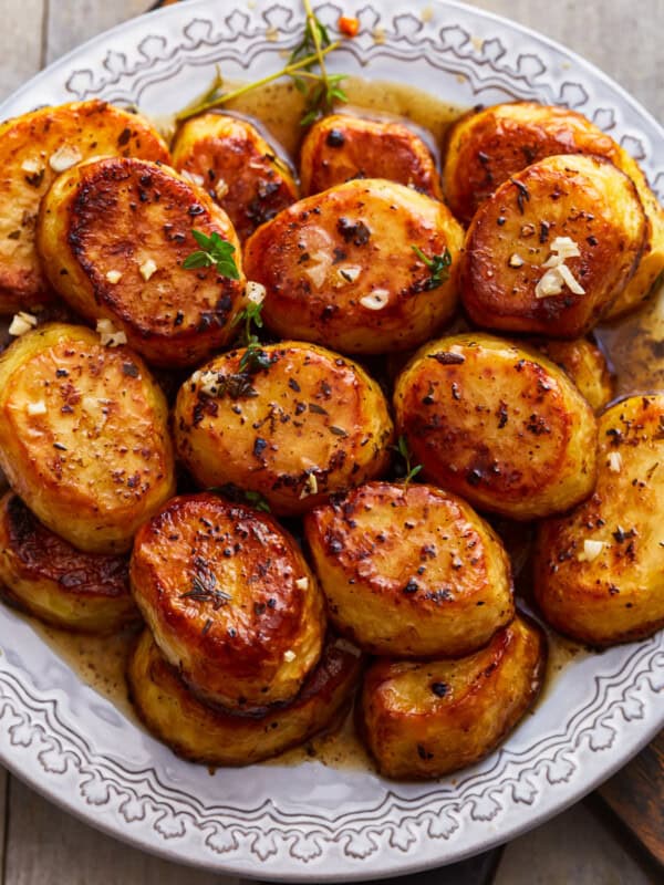 A plate of roasted potatoes on a wooden table.