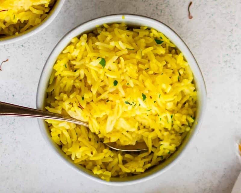 two bowls of yellow rice with a spoon.