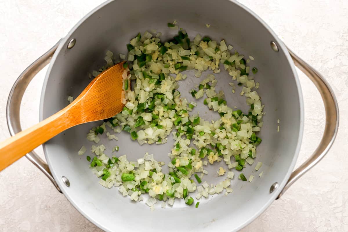 sauteed onion, garlic, and jalapeno in a dutch oven with a wooden spoon.