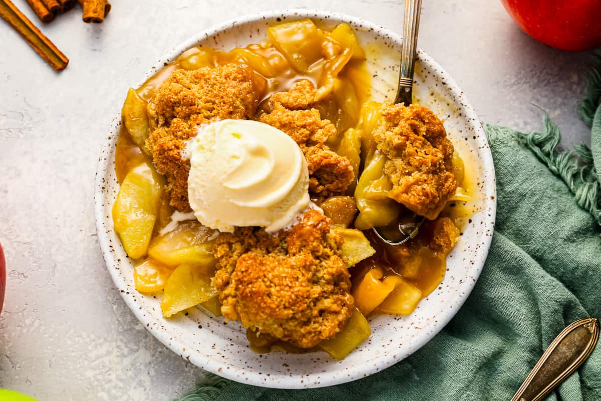 a plate of apple cobbler with a crumbly topping and ice cream.