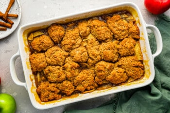 Apple cobbler, prepared in a baking dish, features delicious apples and a sprinkling of cinnamon for added flavor.