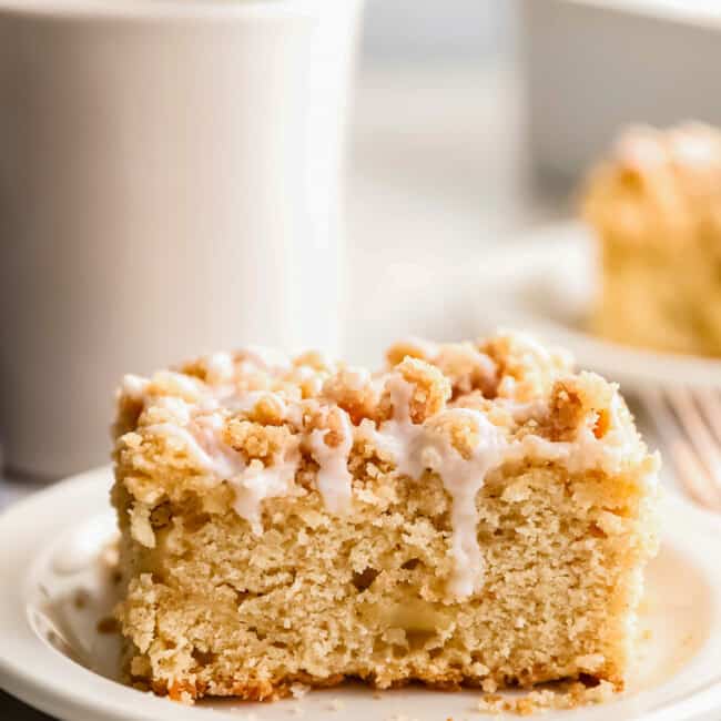 An irresistible apple coffee cake on a plate with a cup of steaming coffee.