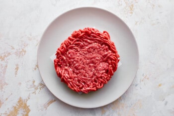 An avocado burger on a white plate.