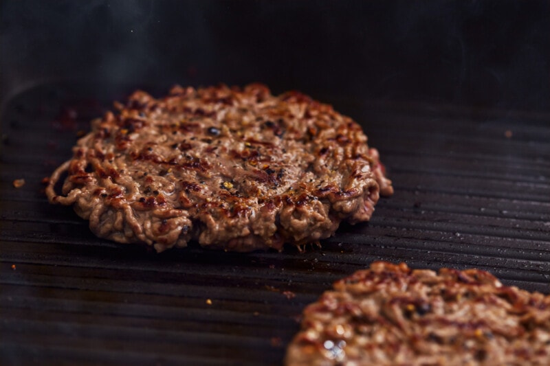 Two avocado burgers are being cooked on a grill.