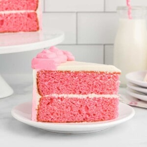 side view of a slice of pink velvet cake on a white plate.