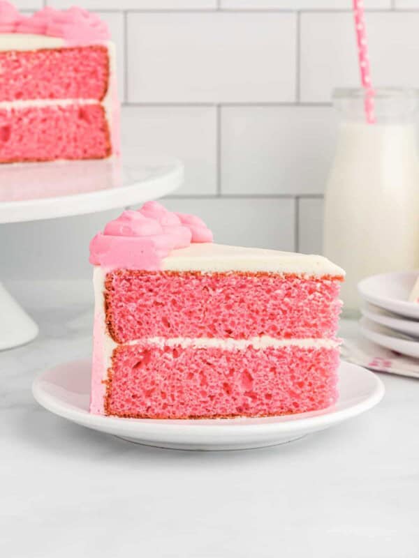 side view of a slice of pink velvet cake on a white plate.