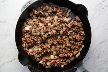 Cheeseburger bombs sizzling in a skillet.