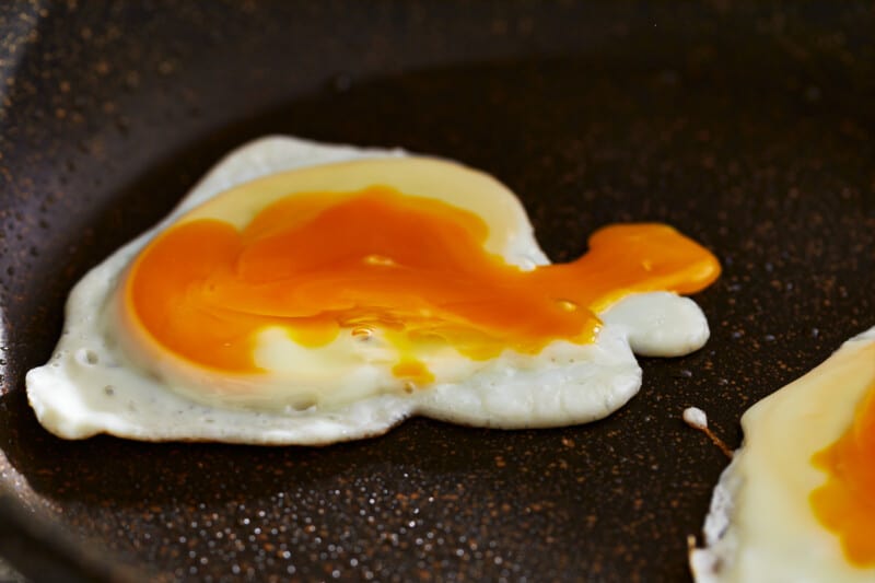 Bagel breakfast sandwich with fried eggs in a frying pan.