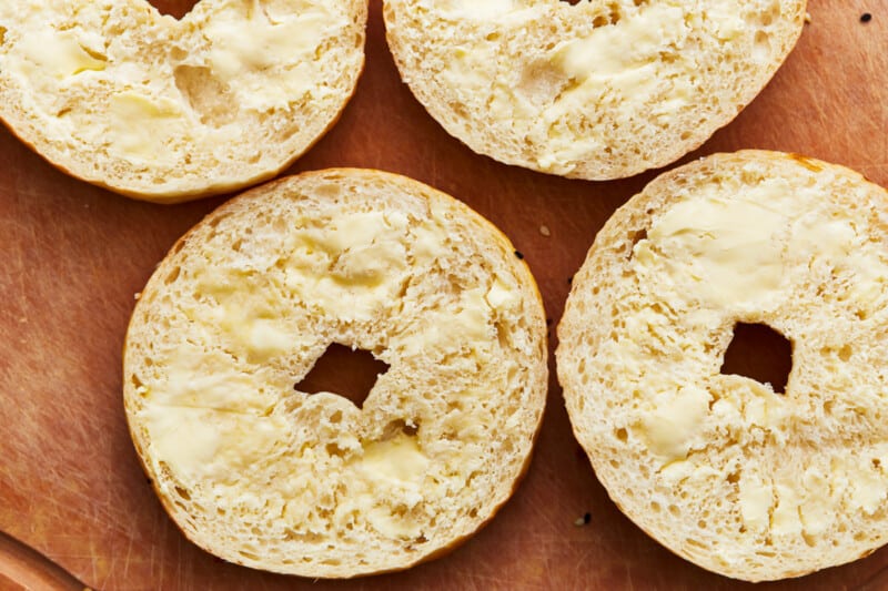 Four bagels on a wooden cutting board.