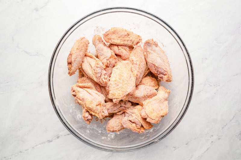 seasoned chicken wings in a glass bowl.