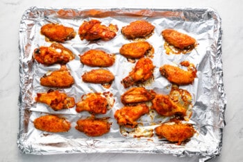 A sheet of aluminum foil with bbq chicken wings on it.