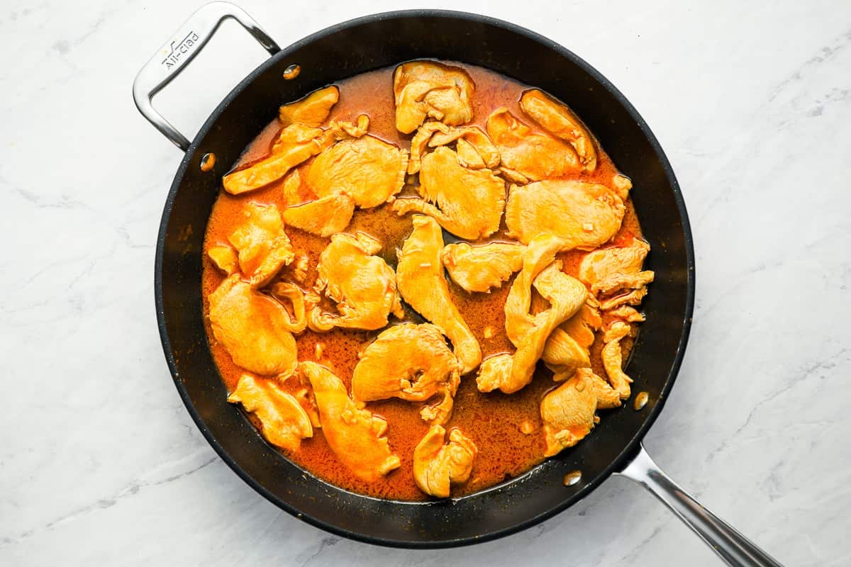 Pieces of buffalo chicken cooking in a pan.