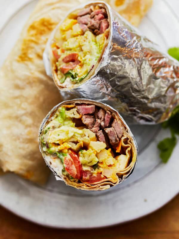 Two california burritos sitting on a plate.