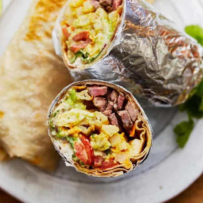 Two California burritos sitting on a plate.