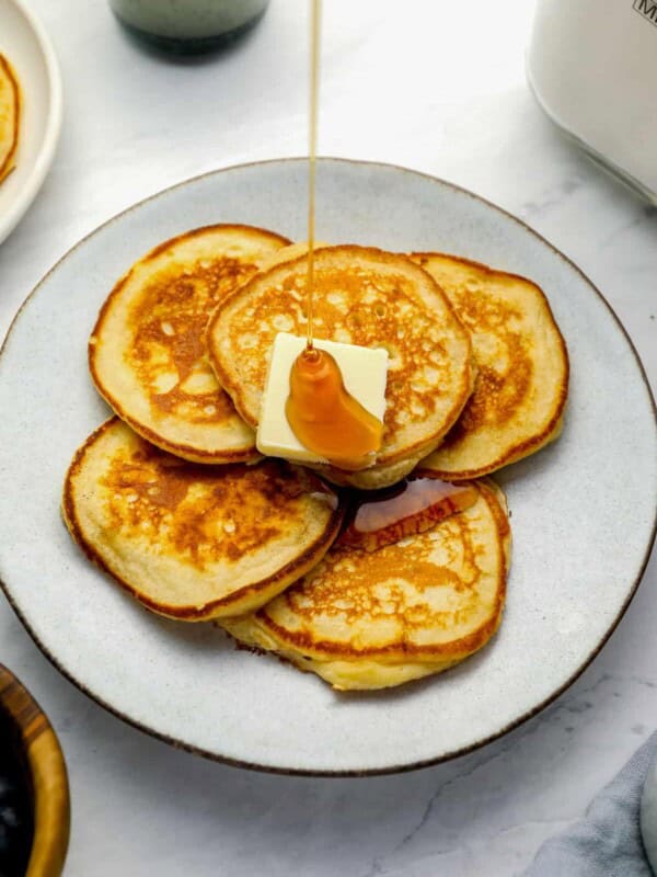 three-quarters view of a plate full of homemade pancakes with butter and syrup.