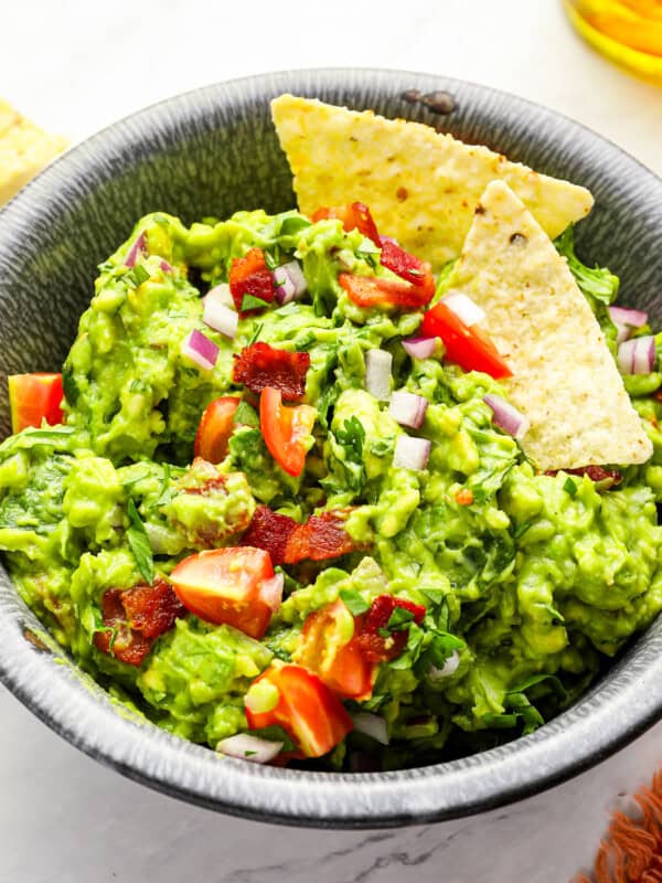 close up of blt guacamole in a bowl with tortilla chips.