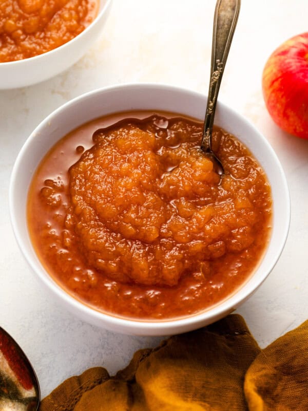 a serving of applesauce in a white bowl with a spoon.