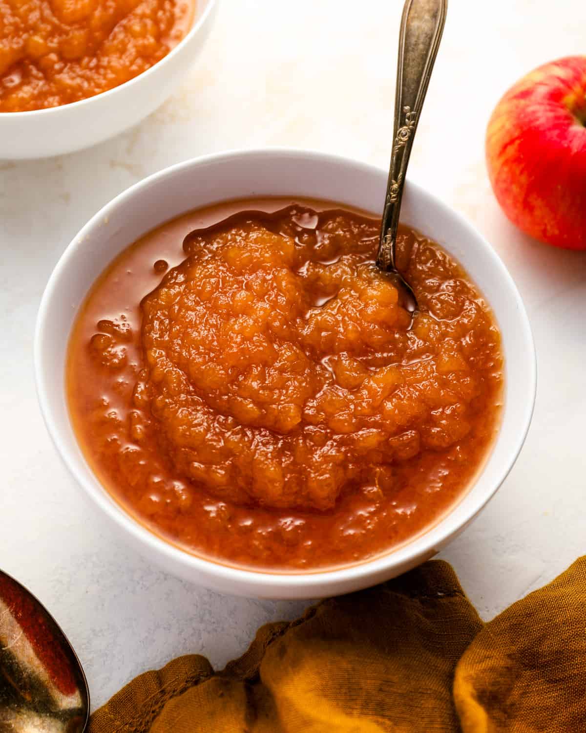 a serving of applesauce in a white bowl with a spoon.