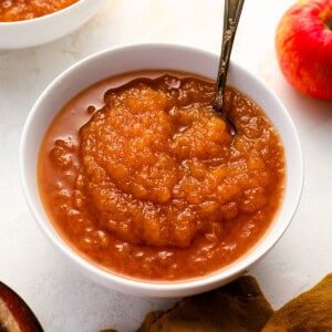 a serving of applesauce in a white bowl with a spoon.