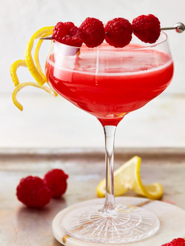 A raspberry lemon drop martini cocktail, garnished with raspberries and lemon.