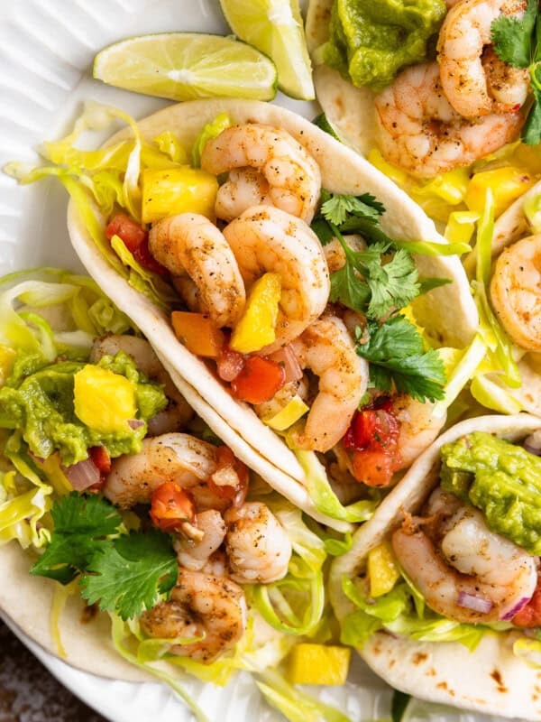 A plate of shrimp tacos with pineapple slaw and guacamole.