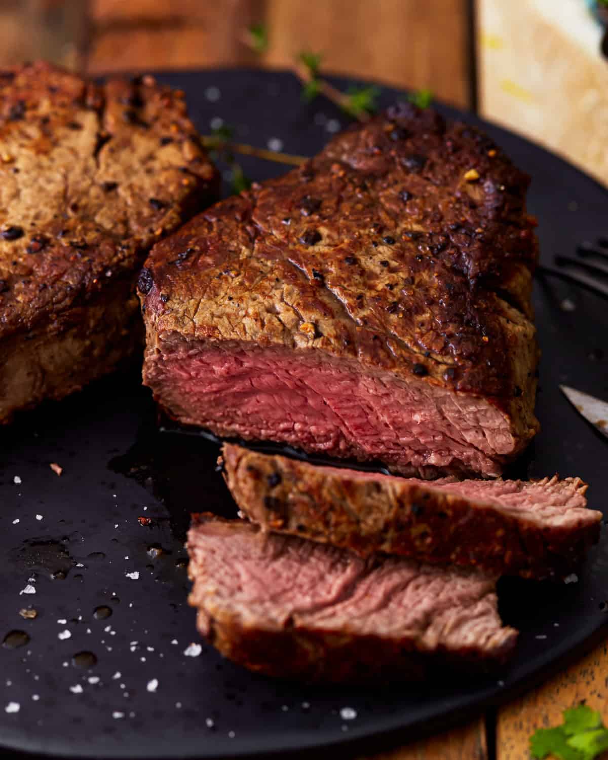 three-quarters view of a partially sliced filet mignon cooked to medium rare.