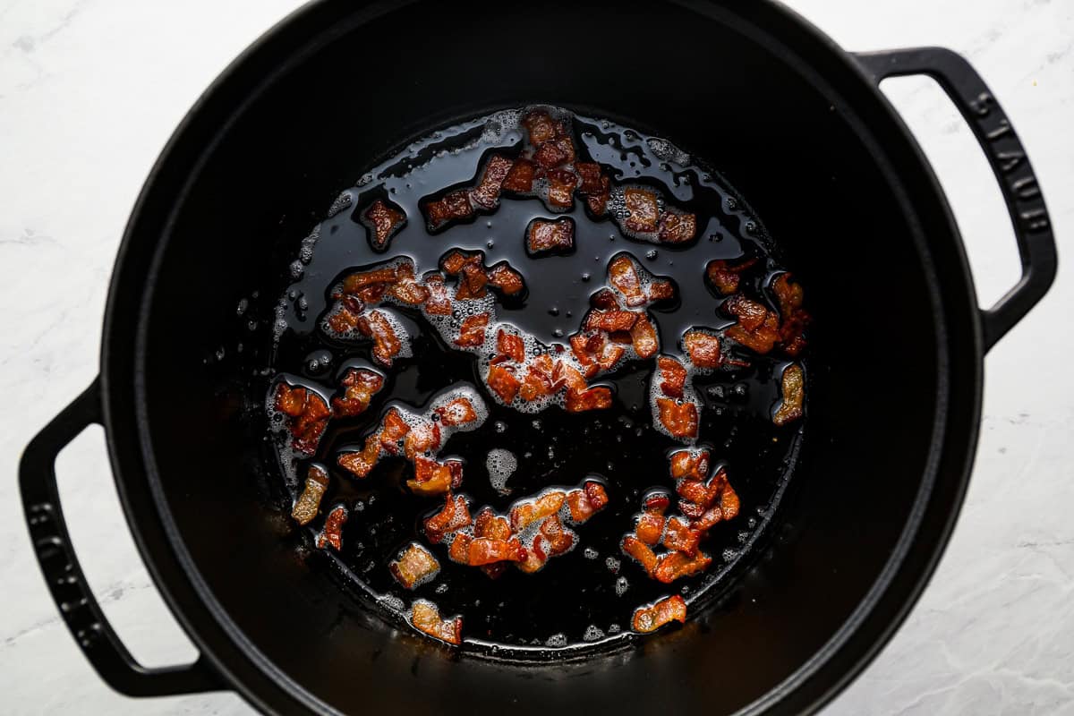 bacon bits cooking in a dutch oven.