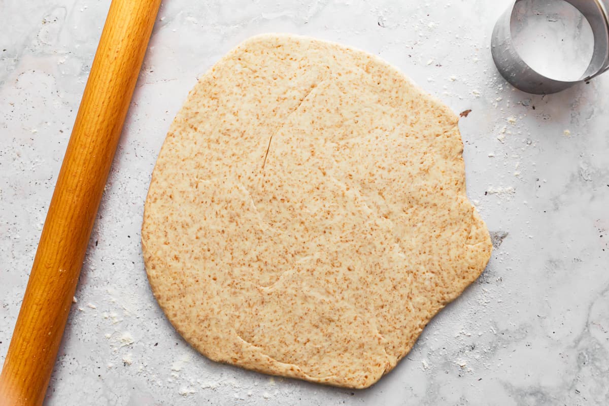 rolled out english muffin dough on a table.