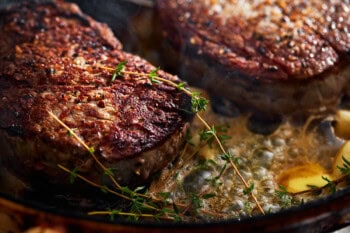 filet mignon in a pan with butter and thyme.