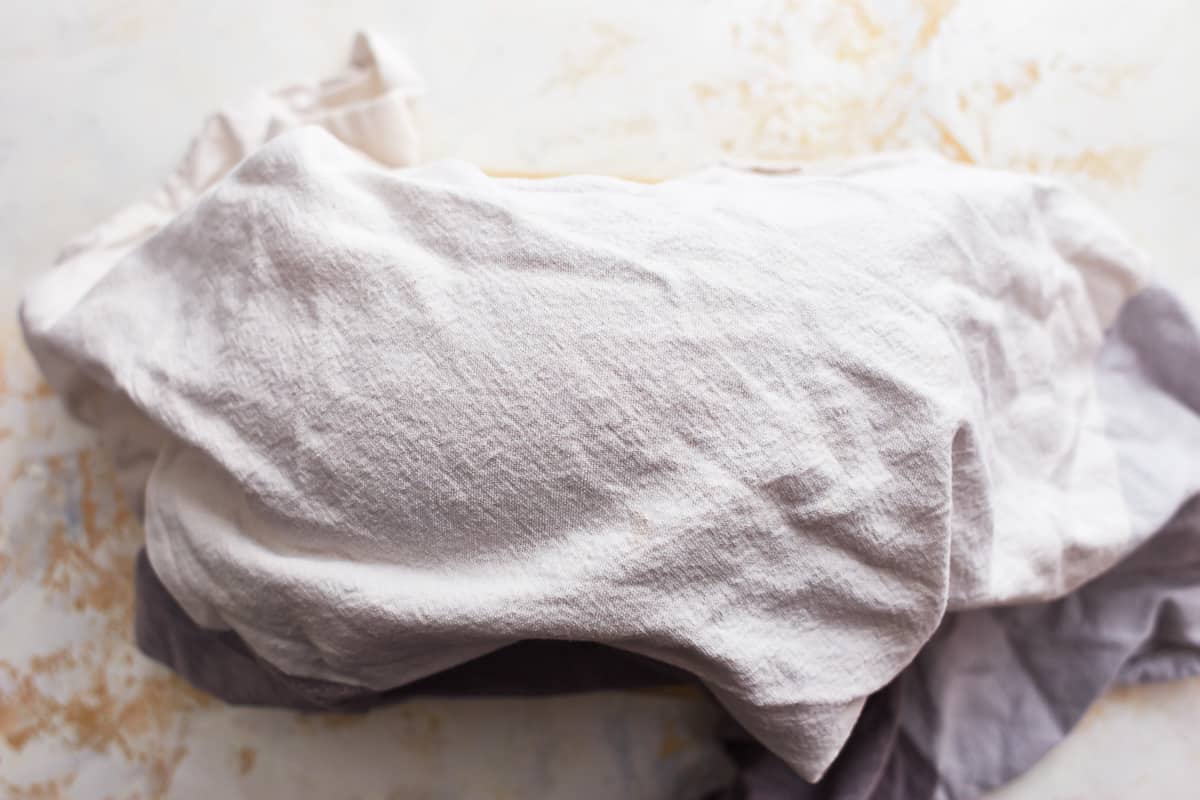 a towel covering a baked loaf of white sandwich bread.