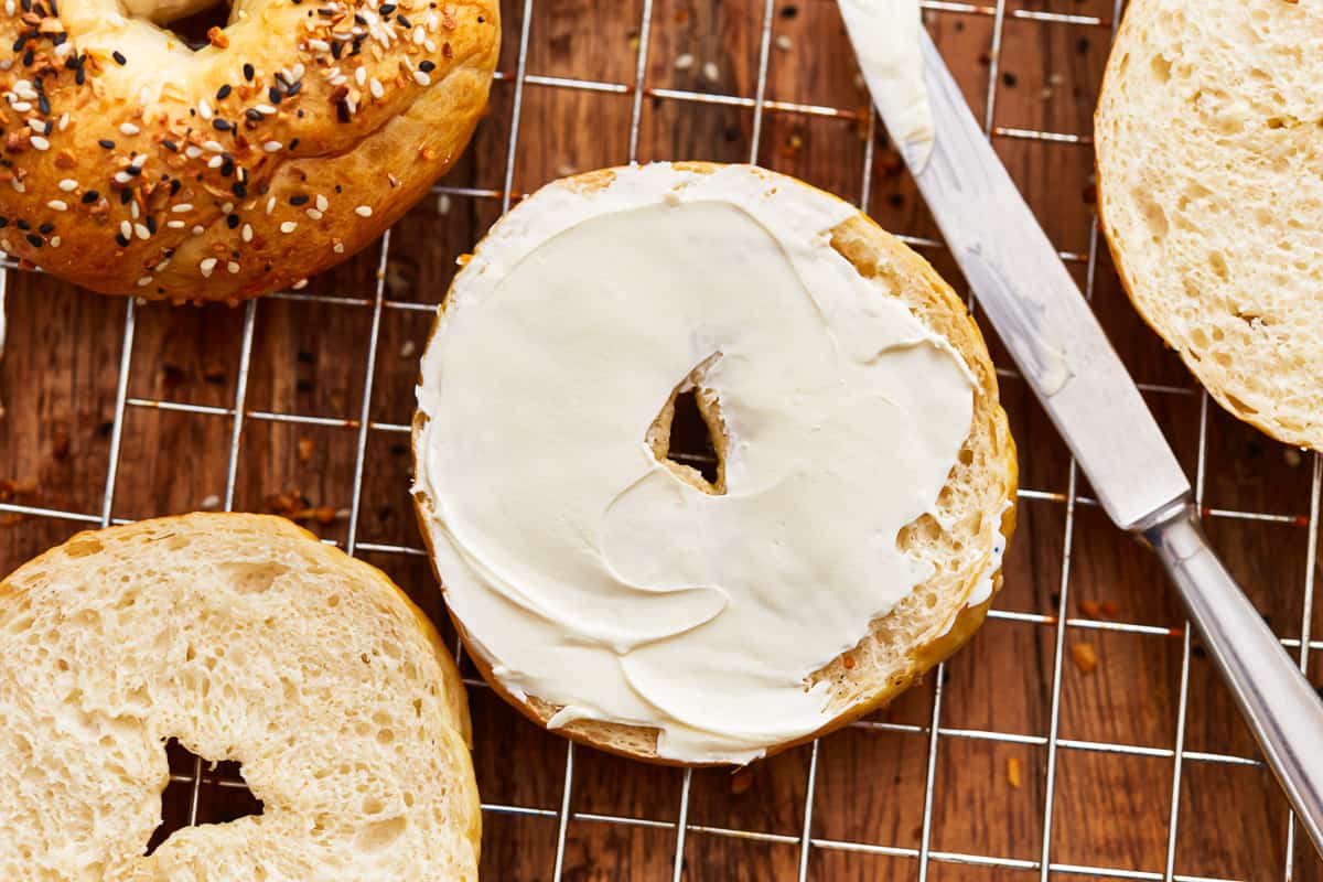 a sliced homemade bagel spread with cream cheese.