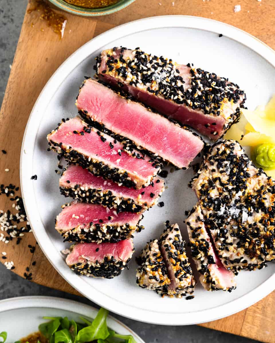 overhead view of a plate of ahi tuna steaks, coated in sesame seeds and sliced thinly.