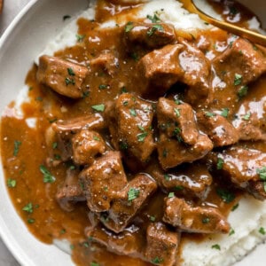 A bowl of beef tips and gravy served over mashed potatoes.